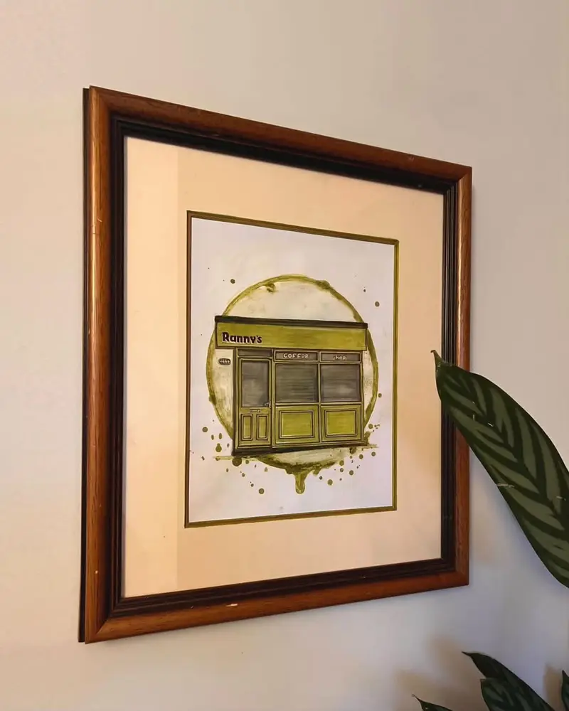 Framed watercolour of the Ranny's shopfront by Sketch Stockport, hung on the shop wall